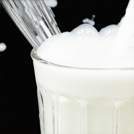 Close-up of a milk frother wand being descaled in a glass of citric acid solution to remove mineral buildup.