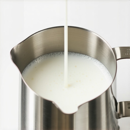 Close up of a steam wand creating a vortex in a milk pitcher for microfoam